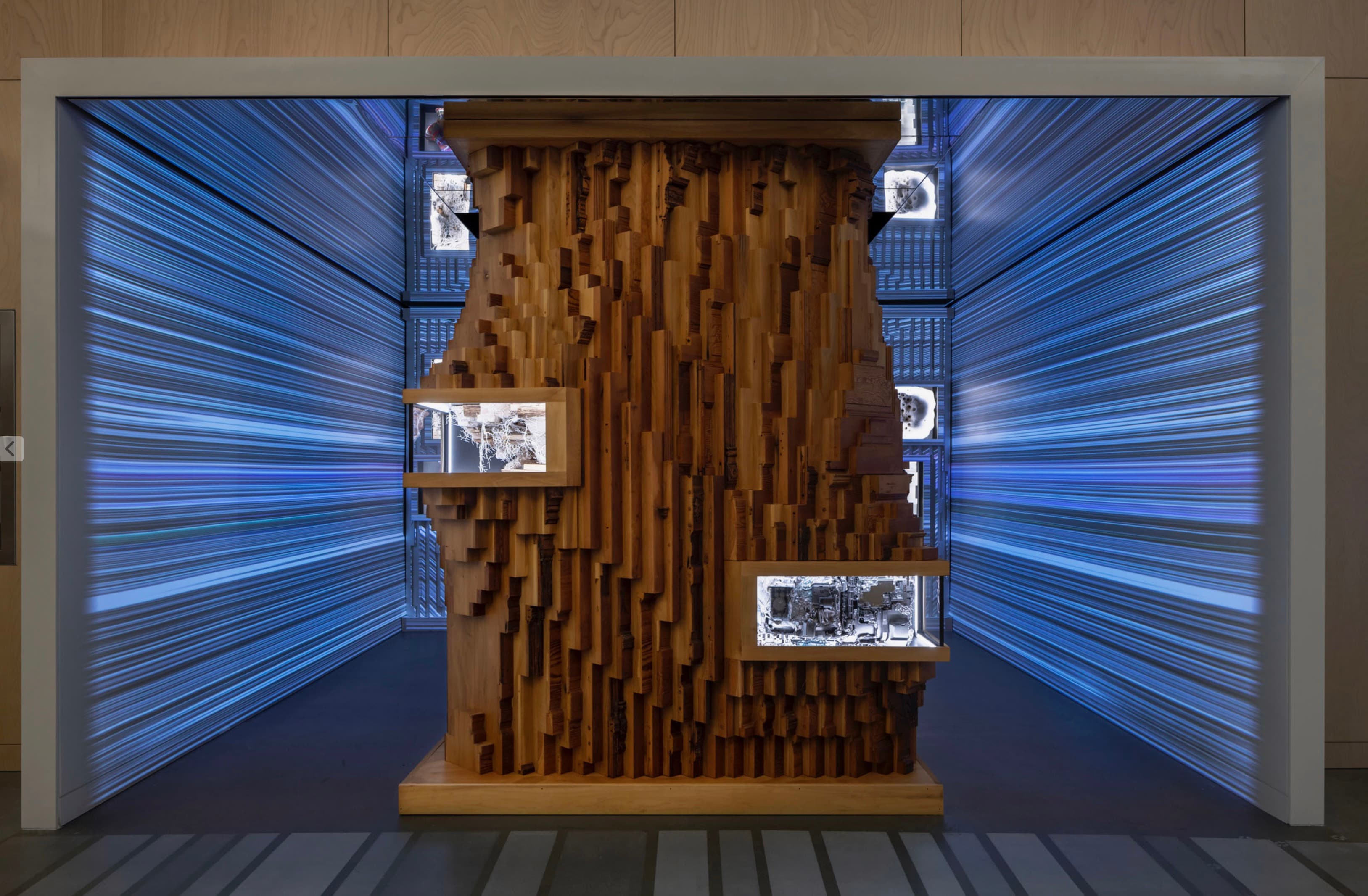 The Recombinant Room wooden sculpture surrounded by blue projected lines